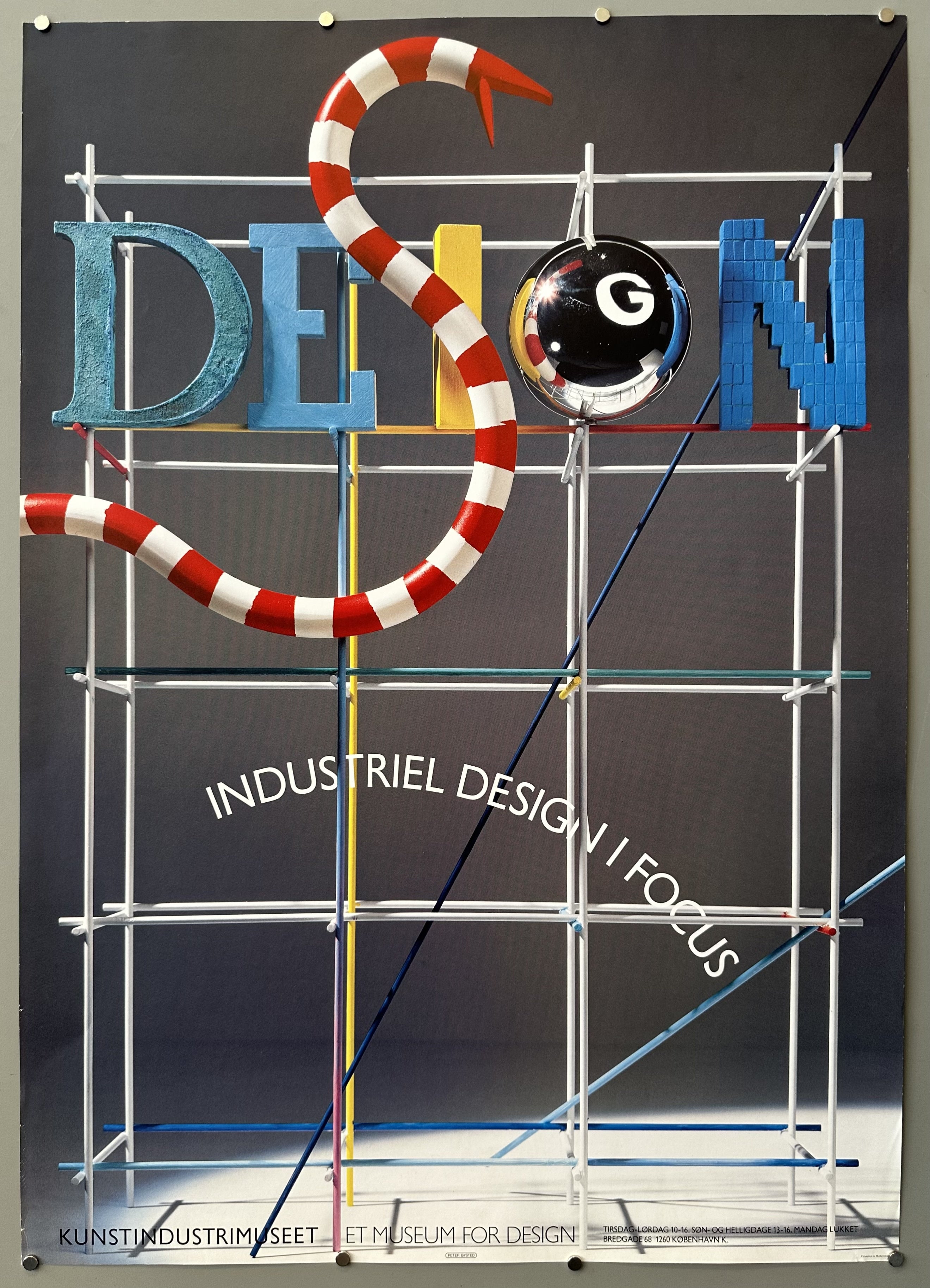 This poster promotes the "Design - Industriel Design in Focus" exhibition held at the Danish Museum of Art & Design (Kunstindustrimuseet et Museum for Design) in Copenhagen, Denmark, during the 1980s.