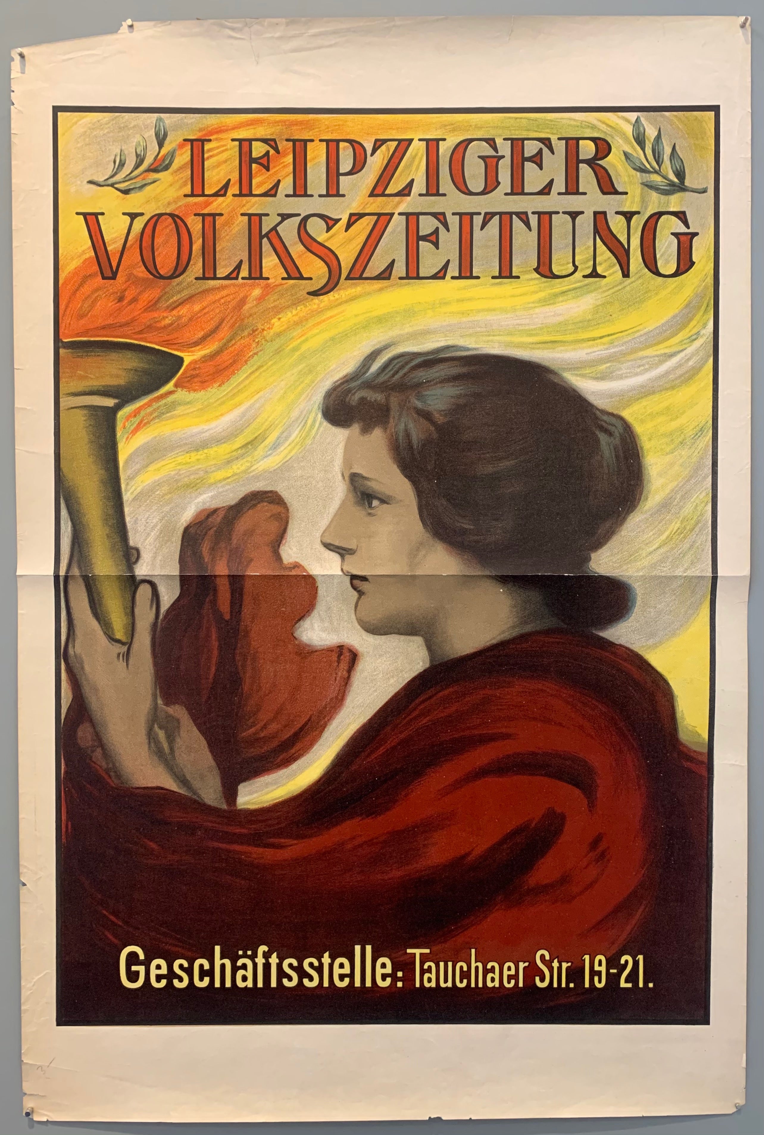 The Leipziger Volkszeitung is a daily regional newspaper in Leipzig, its first publication was on October 1st, 1894. The newspaper has a long history with social democracy. This poster advertises both the newspaper and where their offices were at the time; Taucher Str. 19-21. Pictured is a woman holding a torch which flames leaping out and around her.