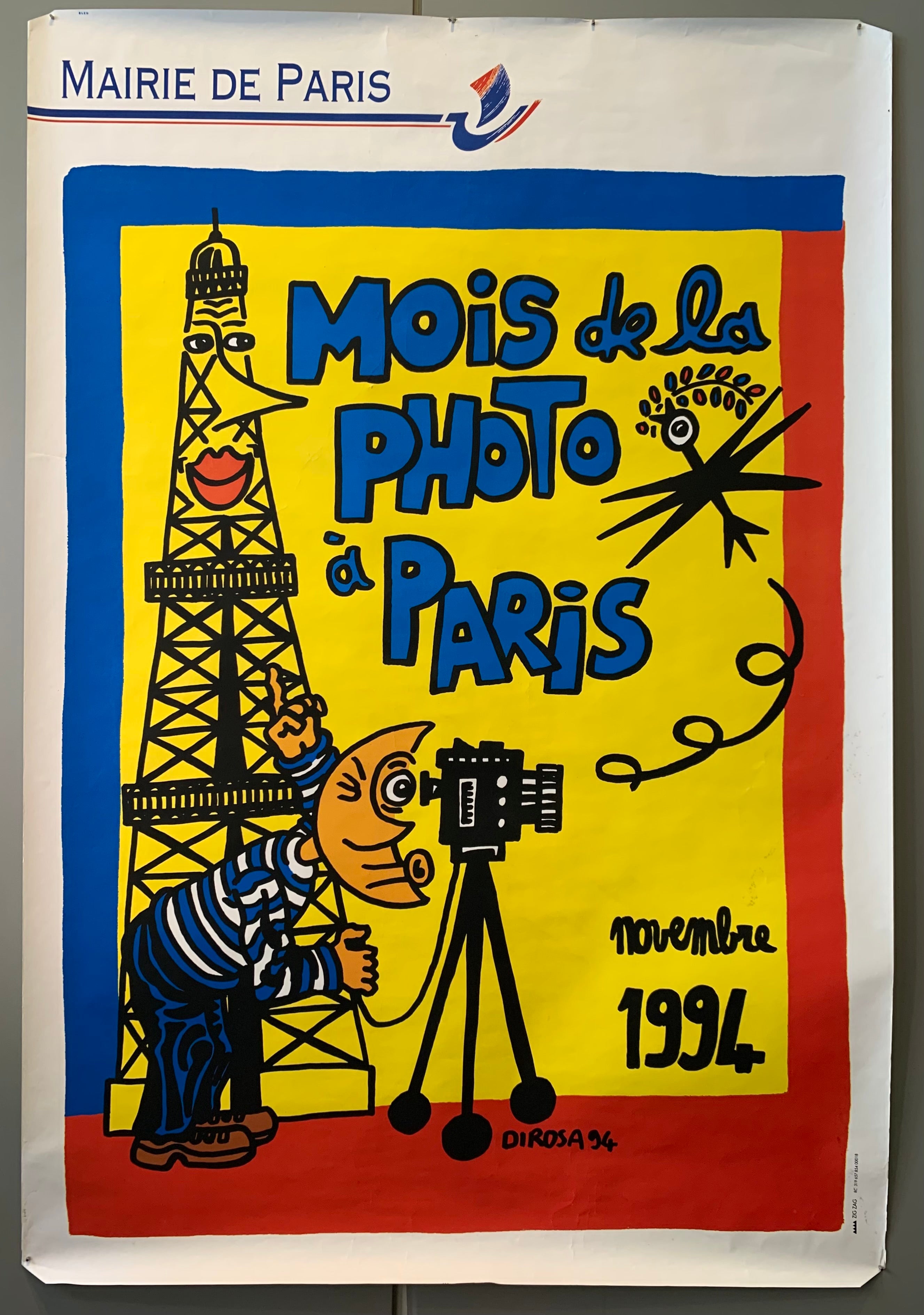A cartoon drawing of a moon-faced man takin a photo in front of the personified Eiffel Tower, yellow, red, and blue background and white border
