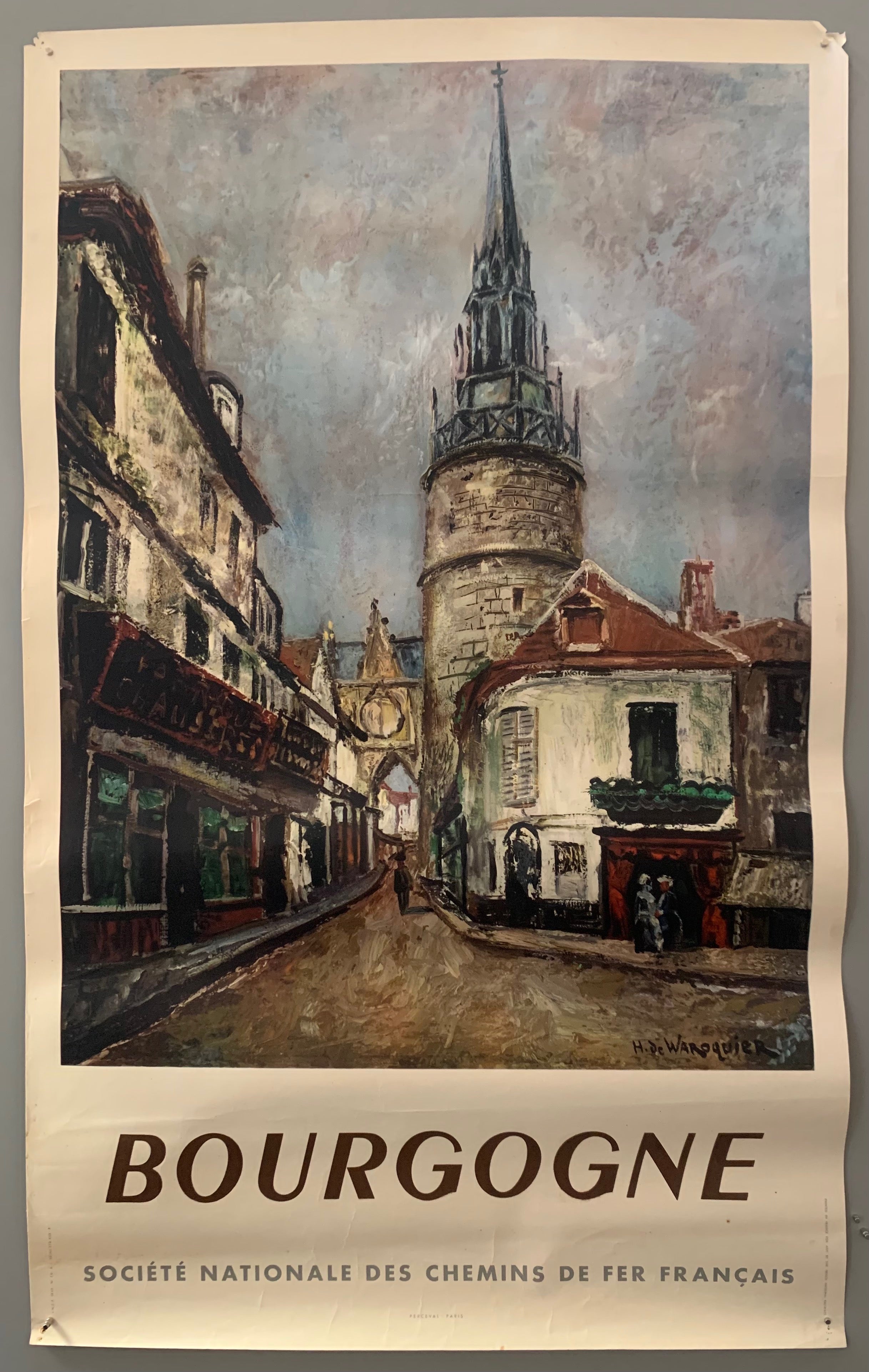 A image in the style of oil painting shows a street leading to a quaint row of shops and a church steeple. The poster has a white border with bold, all-caps, brown and grey writing.