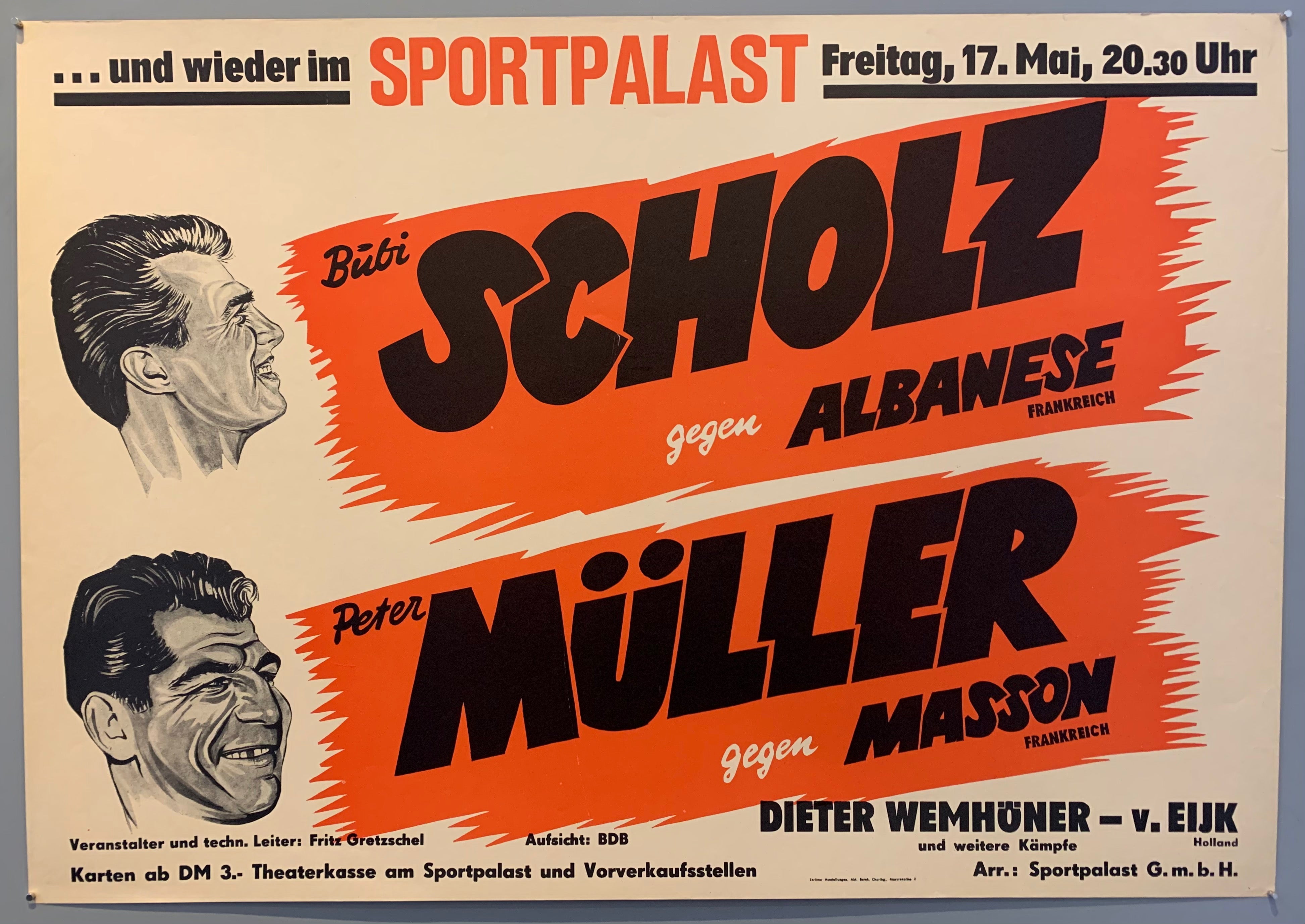 Poster shows drawn faces of both wrestlers next to the names over red stripes.