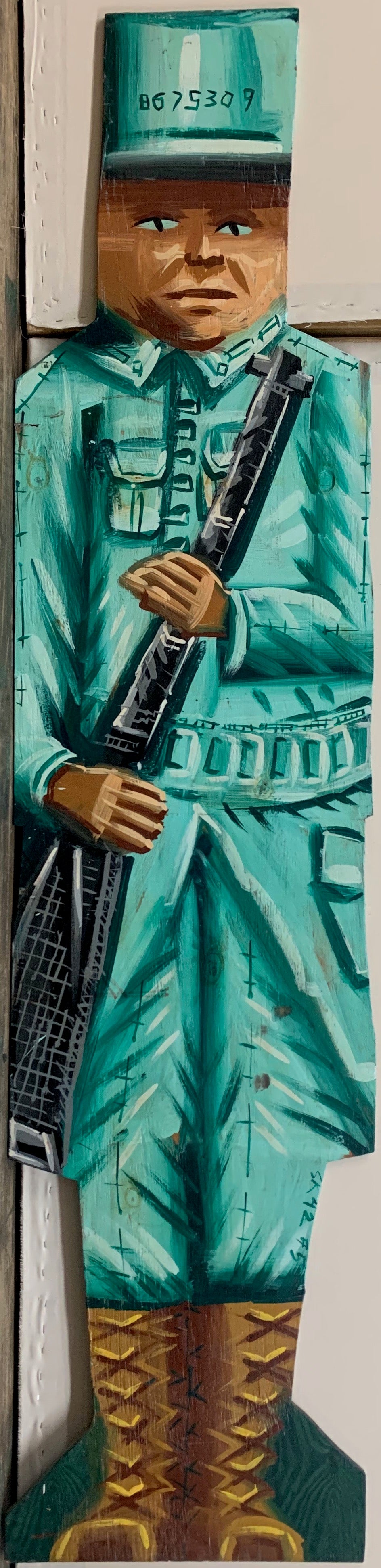 A Steve Keene double-sided painting of a soldier in a teal uniform and brown boots carrying a black rifle.