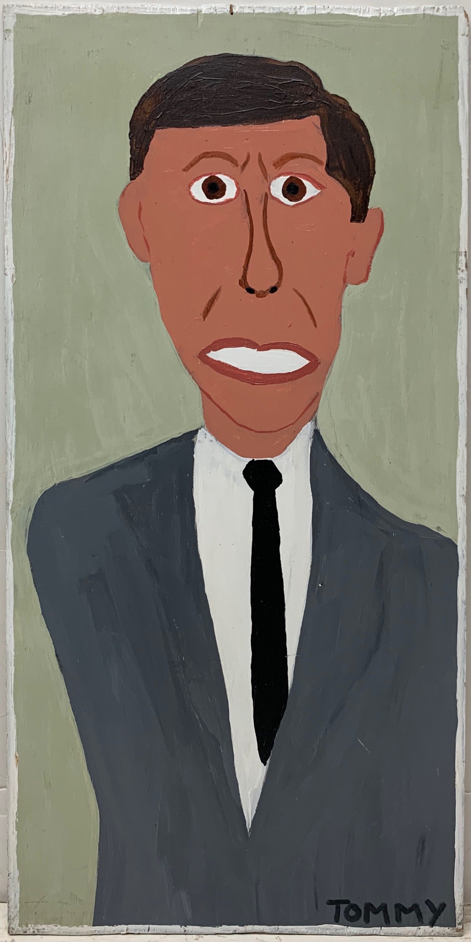 A Tommy Cheng portrait of JFK with his teeth clenched, wearing a gray suit.