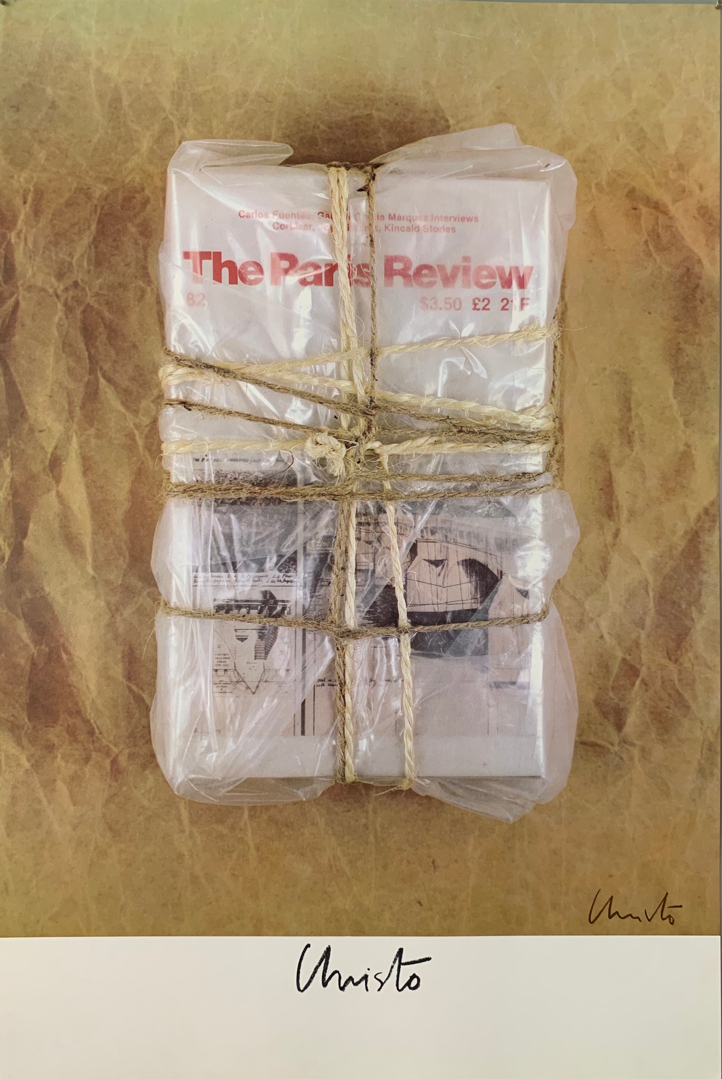 A photograph of a plastic wrapped stack of The Paris Review wrapped in twine on a tan background.