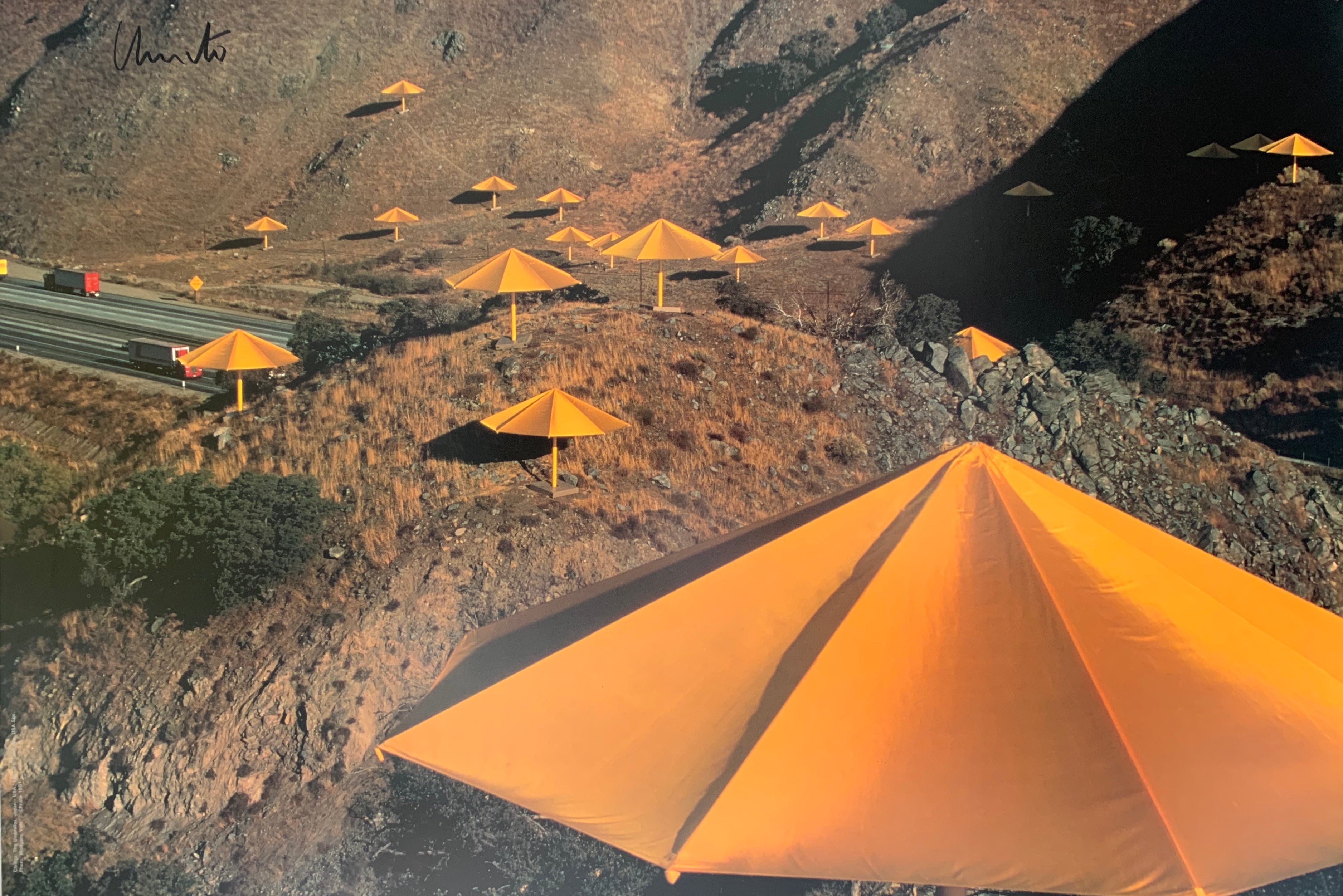 A vibrant colored photograph of a smatter of yellow umbrellas against brown hills.