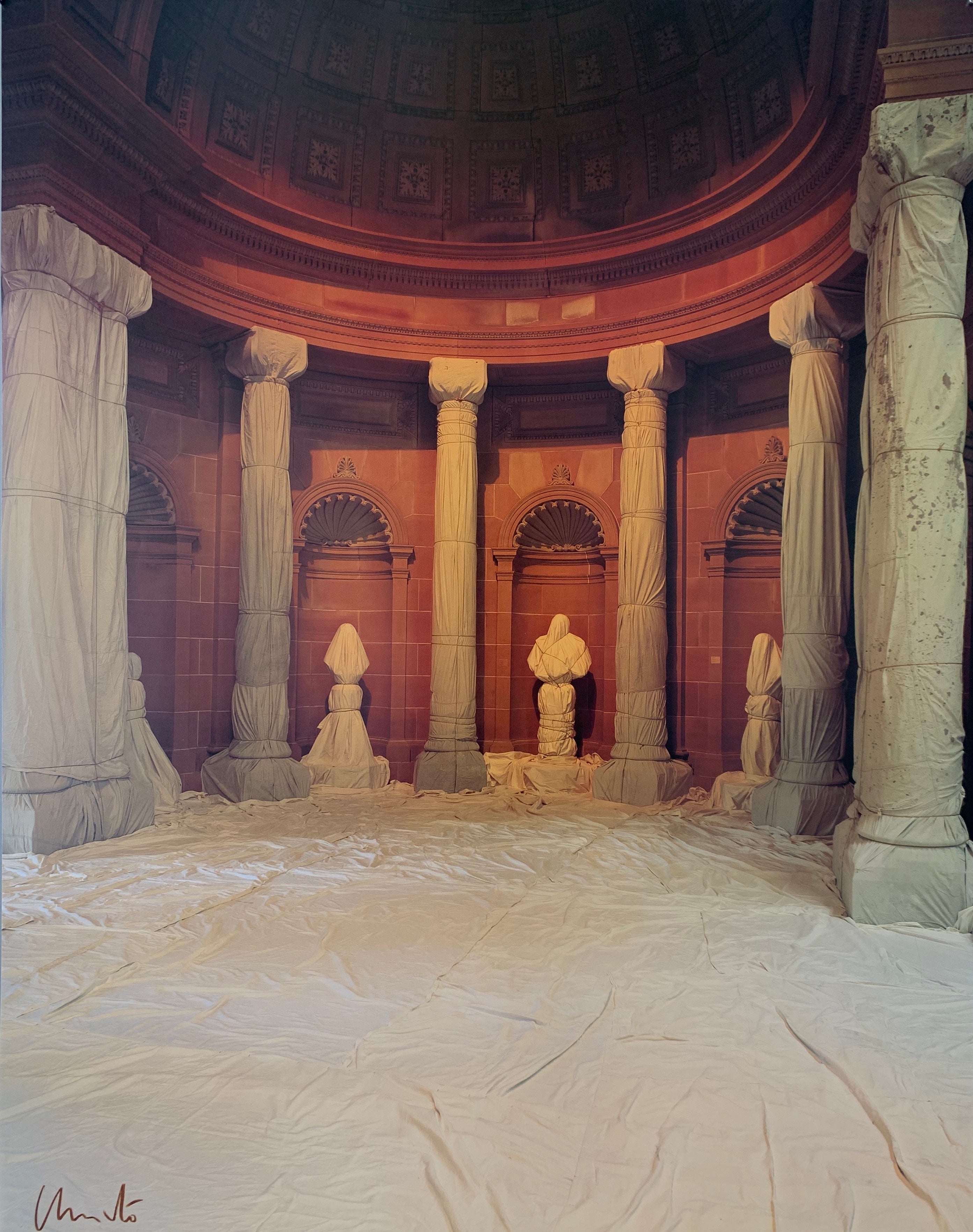 A colored photograph of wrapped columns in a domed red room.