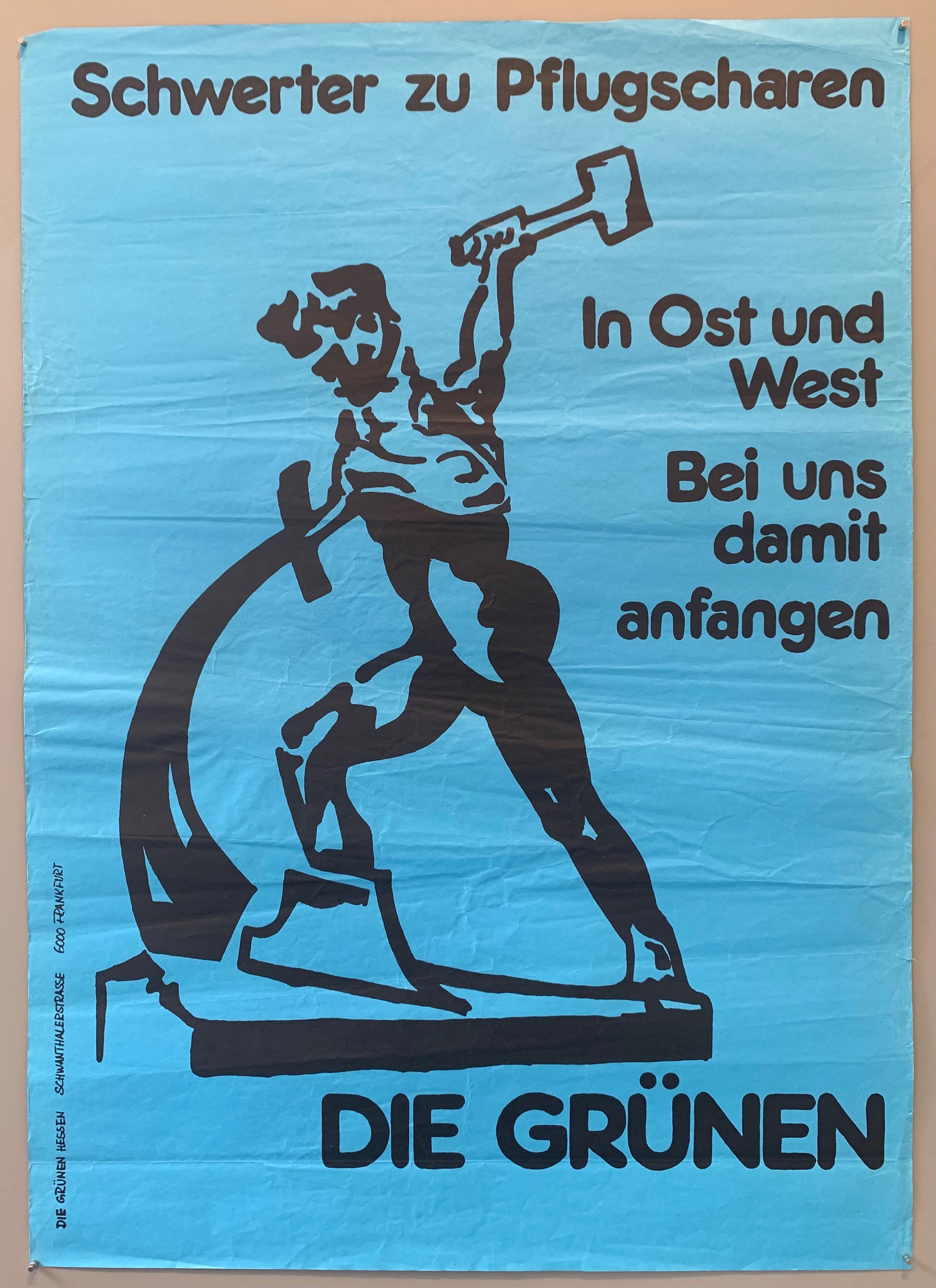 Poster shows a soviet image combined with a quote from the Bible which became a symbol of the GDR peace movement. The man shown is a depiction of the bronze sculpture by the Russian sculptor Yevgeny Wiktorowith Wutschetisch. “Let us forge our swords into plowshares” is a reference to the Old Testament.