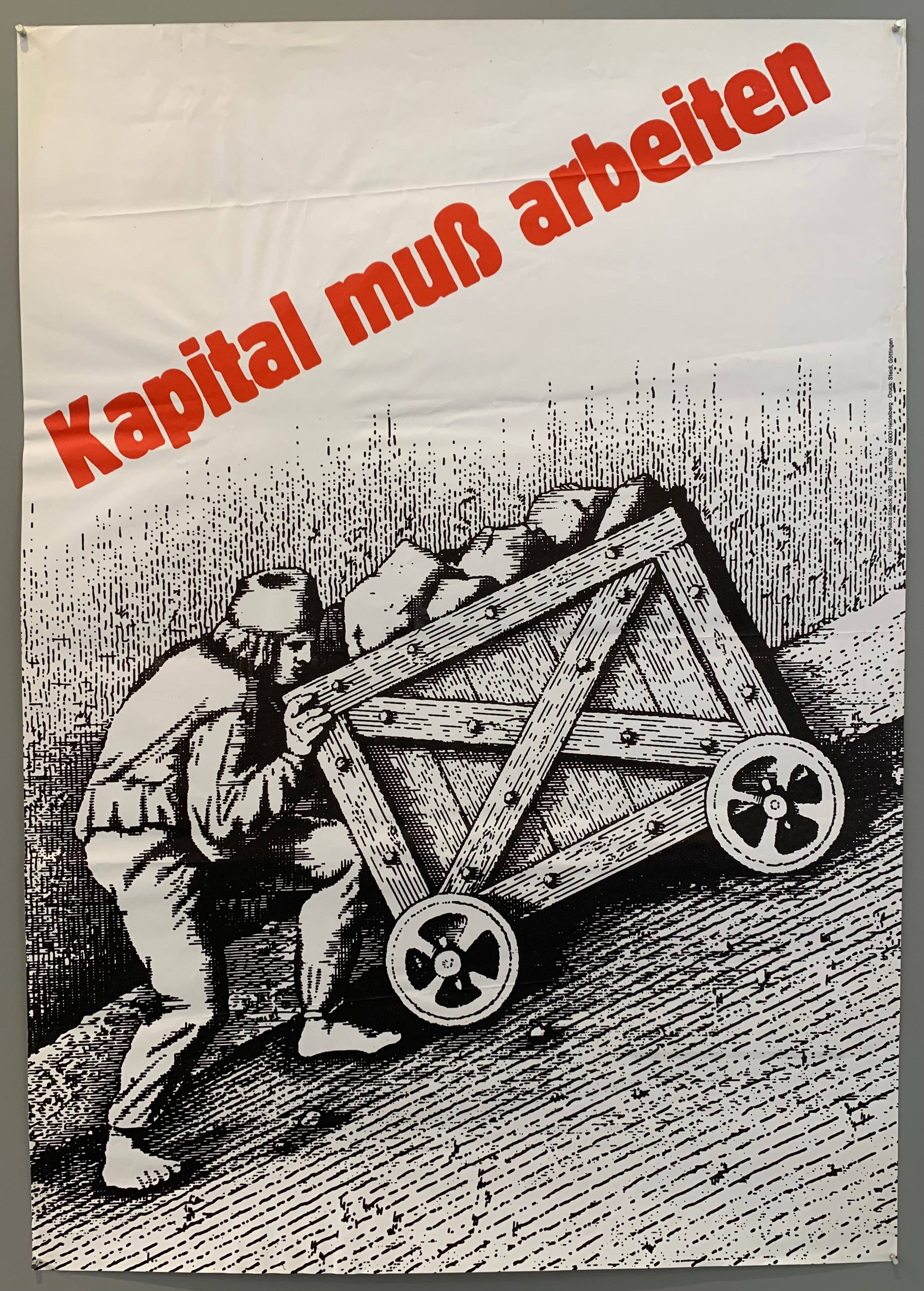 An illustration of a man struggling to push a crate filled with bags of money up a steep incline. Red lettering is pictured above him.