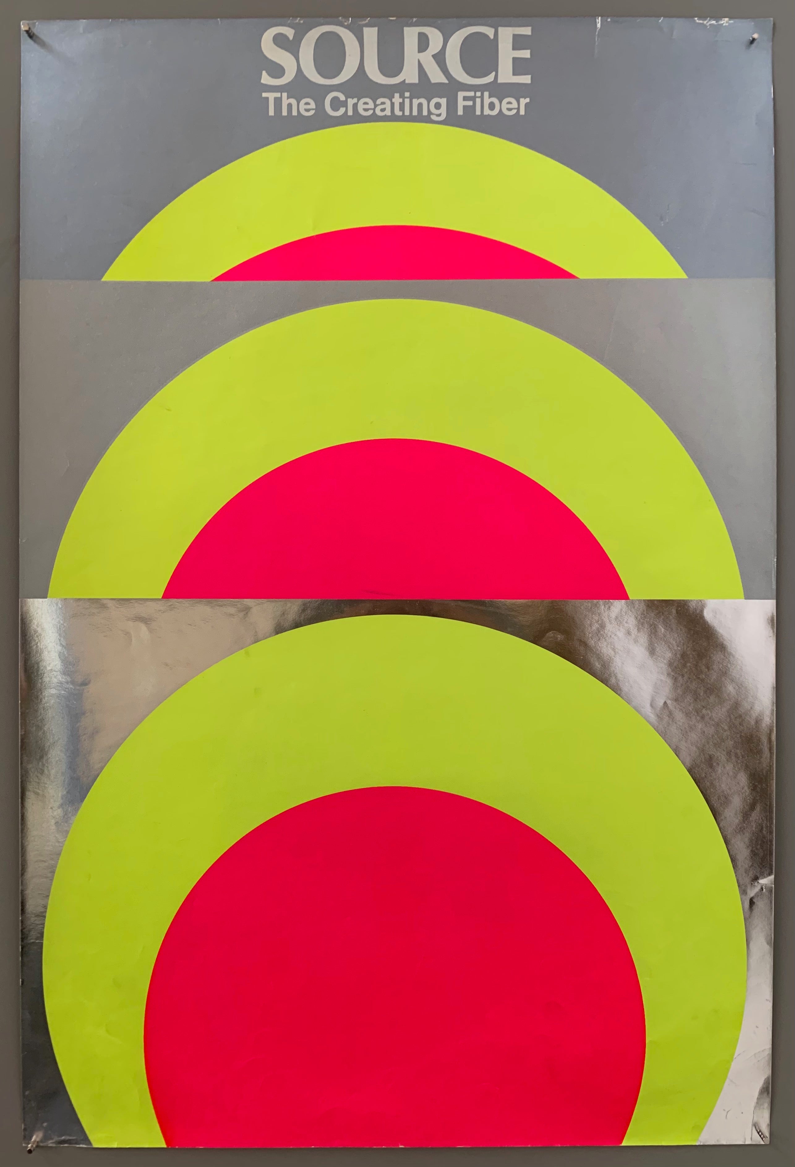 A series of differently sized panels are shown, each one revealing more of a green and pink circle. The panels are made out of different materials, a metallic silver, a matte grey, and a beautifully reflective mylar.