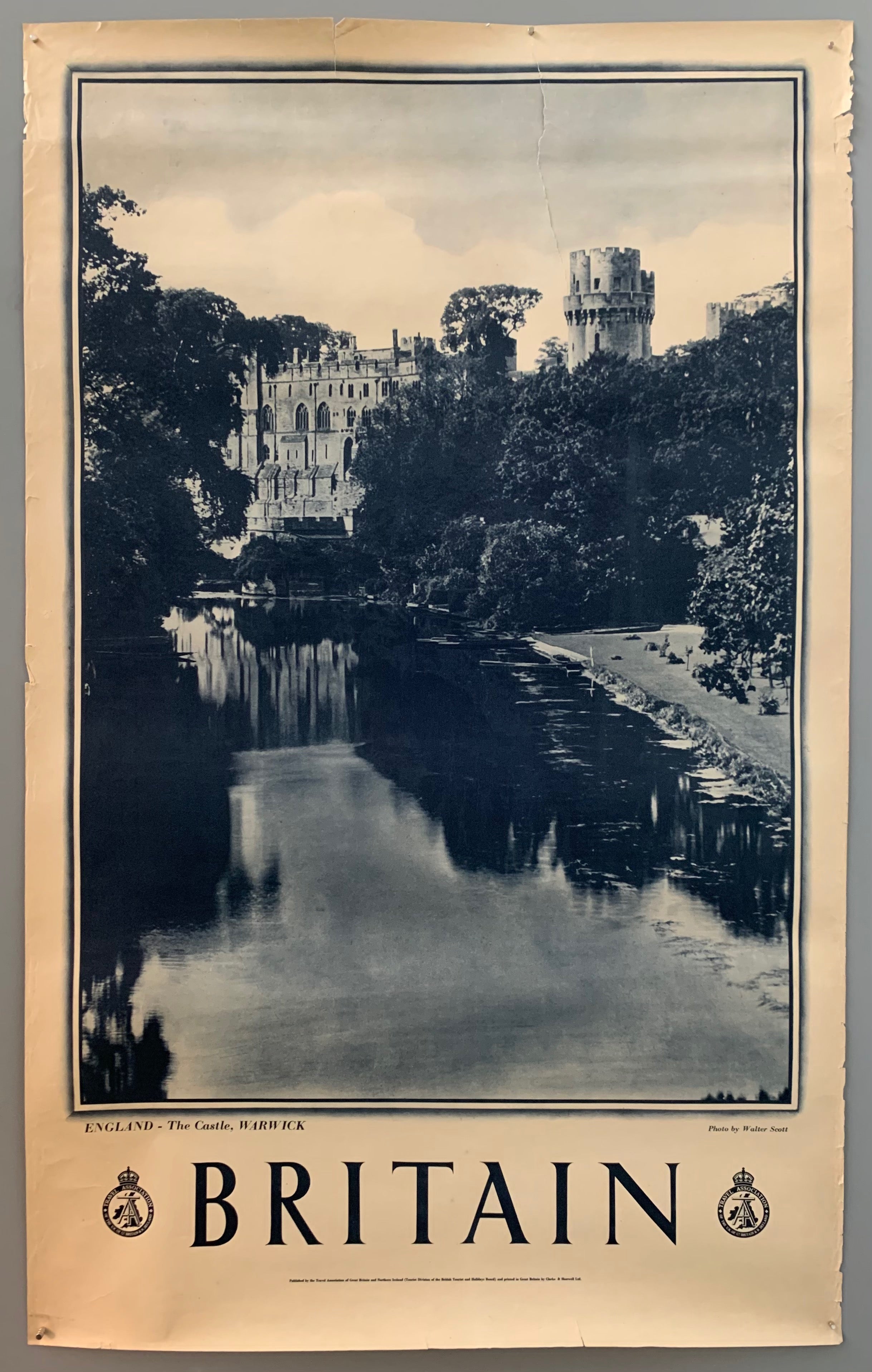 This poster is sepia toned with bold black-and-white writing at the bottom. The photograph takes up the majority of the page.The photograph contains a view of a serene riverbank. The river is framed by trees and in the background a cathedral is shown.