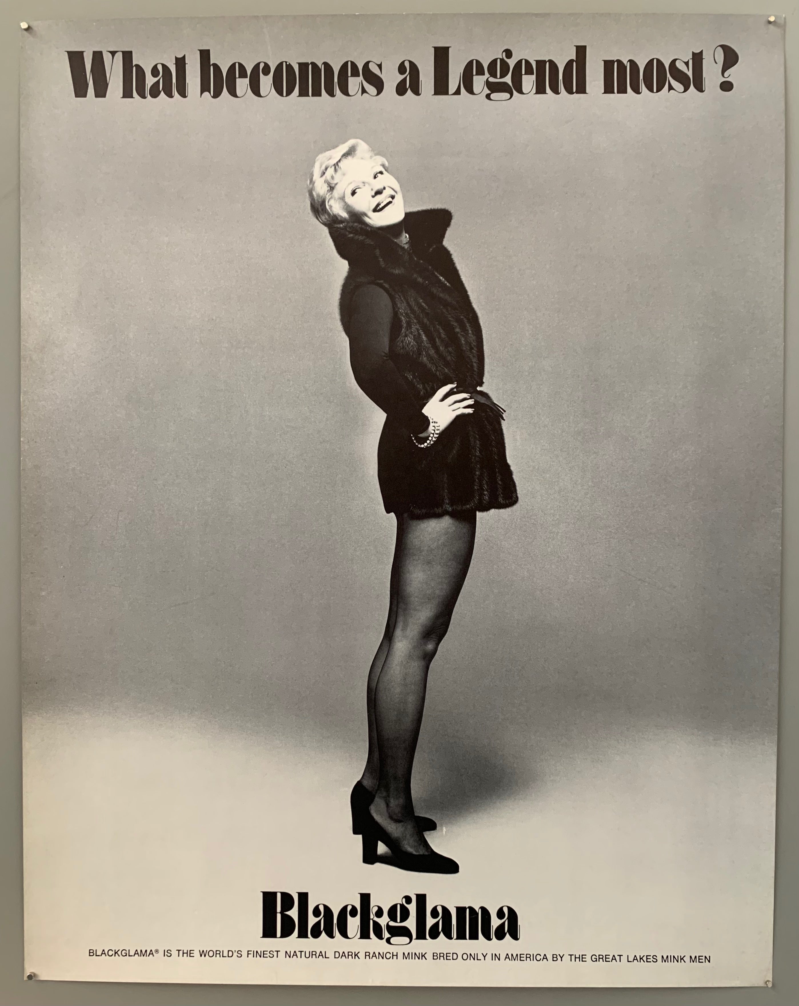 A woman in a mink vest and tights looks goofily behind her. The text is on the top and the bottom in black.