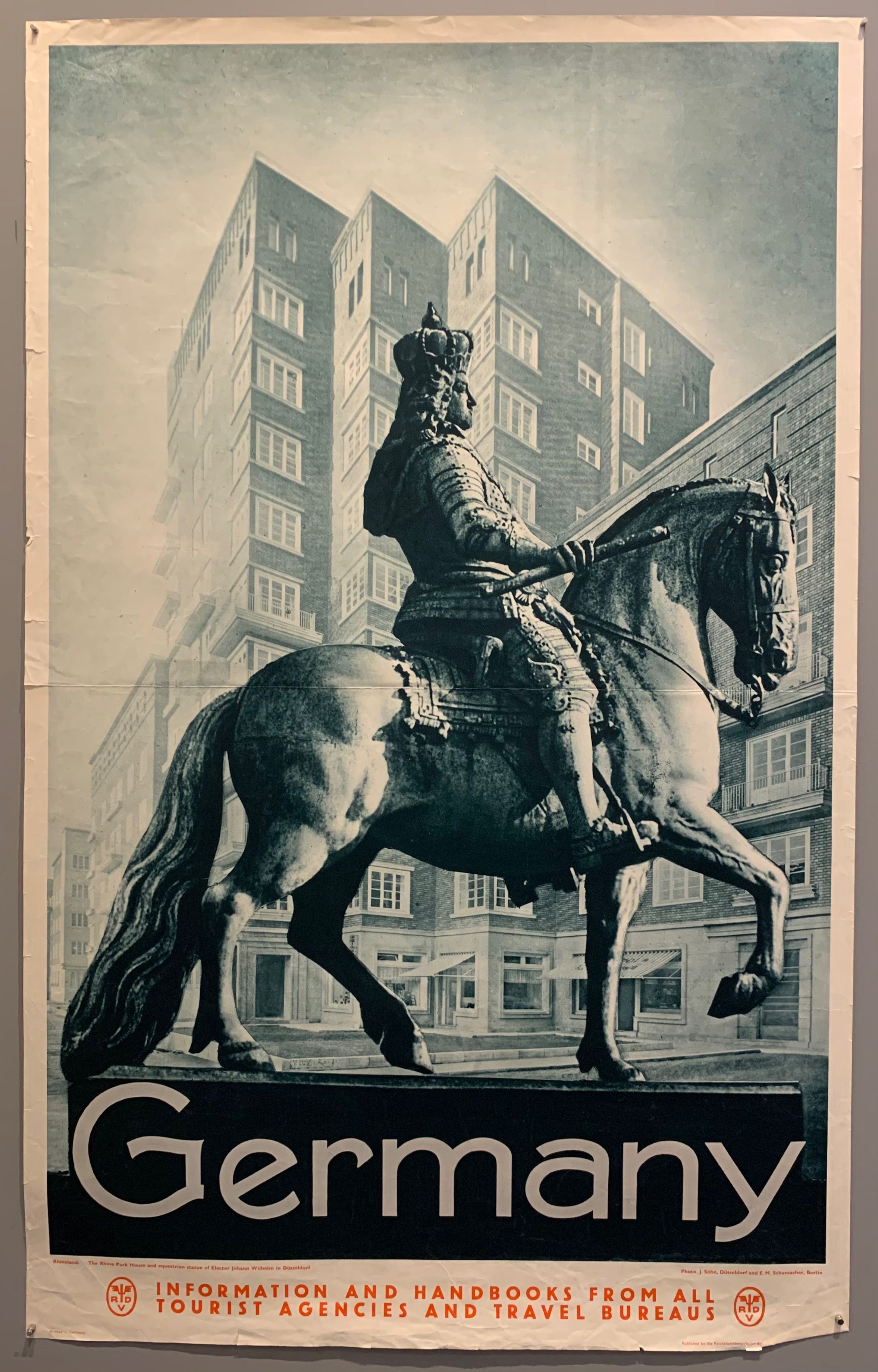 Poster shows a picture of Elector Palatine, Johann Wilhelm riding his horse through the streets of Düsseldorf in front of the Rhine park house.
