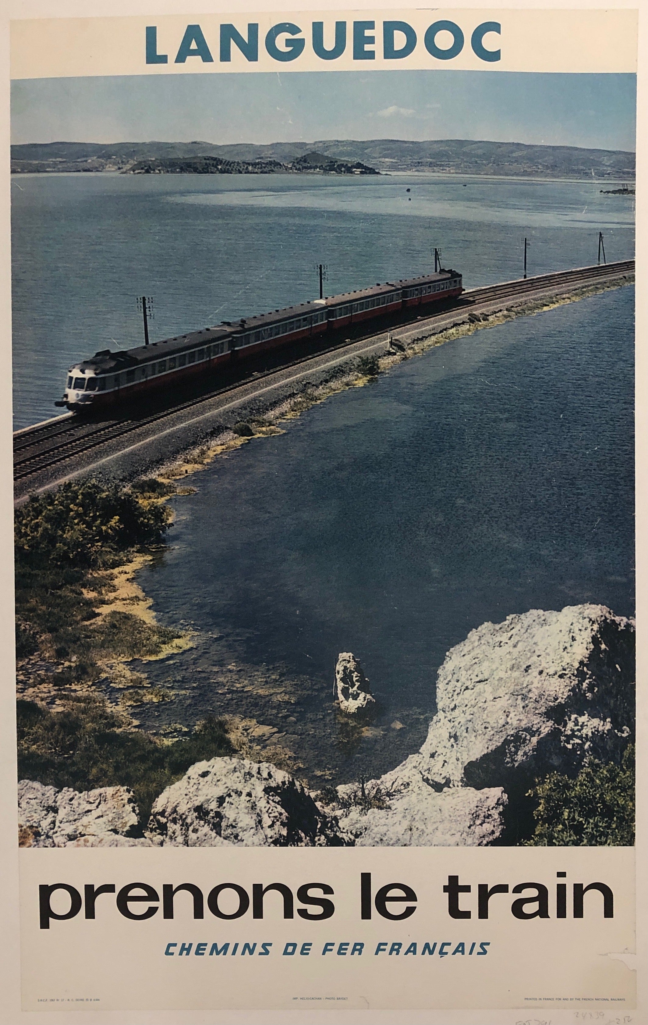 Poster of a black train driving down a railway track across the water.